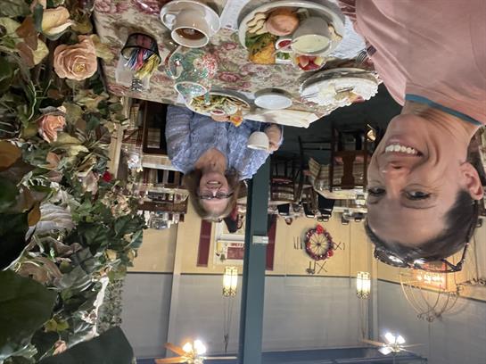 Two friends share a meal in a cafe adorned with beautiful floral decorations.