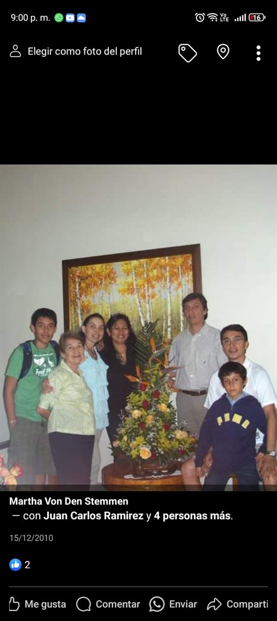A family poses together around a colorful flower arrangement indoors.