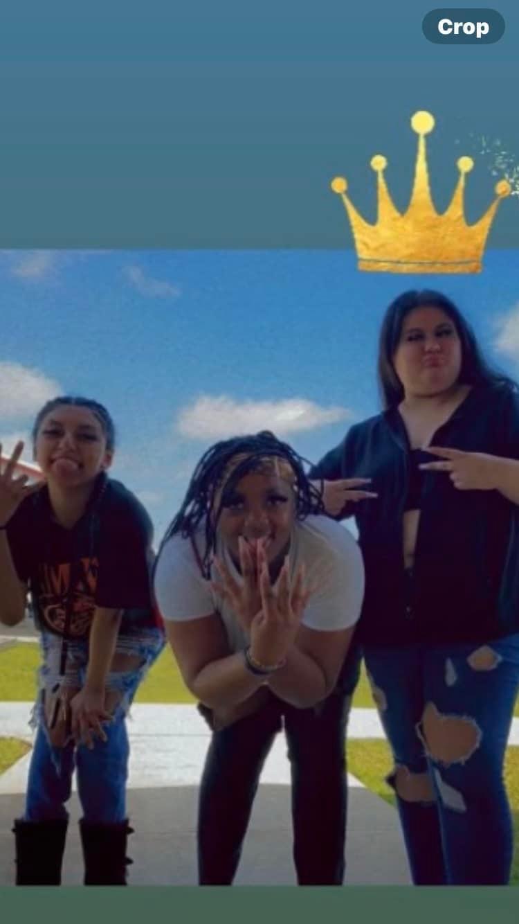 Three friends are enjoying a bright, sunny day outdoors while posing playfully together.