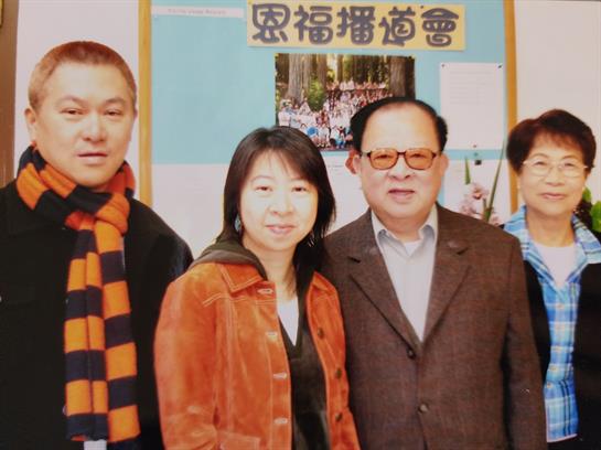 Four people stand together, smiling, in a cultural center during a community event.