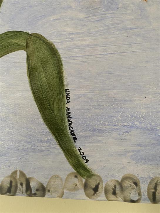 An artist's signature appears beside green leaves on a pale blue background, enhancing the piece.