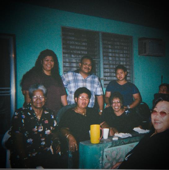 Friends and family gather around a table enjoying food and lively conversation in a cozy room.