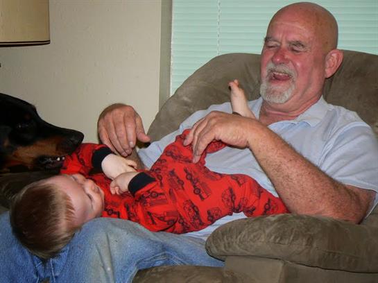 A joyful grandfather enjoys playful moments with his grandson in a comfortable living room.