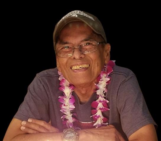 A joyful elderly man enjoys a gathering, wearing a colorful lei and relaxed clothes.