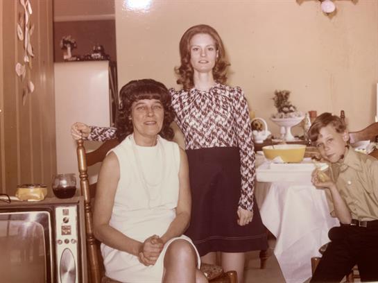Three people posed in a cozy living room with vibrant 1970s vintage decor.