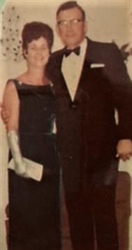 A couple dressed in formal wear enjoys a joyful moment at a celebration in the 1960s.