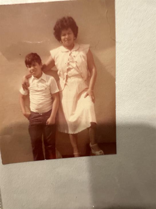 Two children stand together, showcasing their vintage outfits while smiling for the camera.