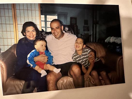 Parents sit on a couch with their children, smiling and enjoying a joyful family moment at home.