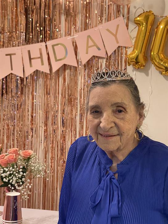 A joyful elder celebrates a milestone birthday with family in a decorated venue filled with love.