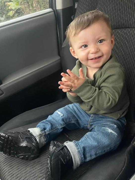 A joyful baby is clapping while sitting in a car seat, enjoying the moment.