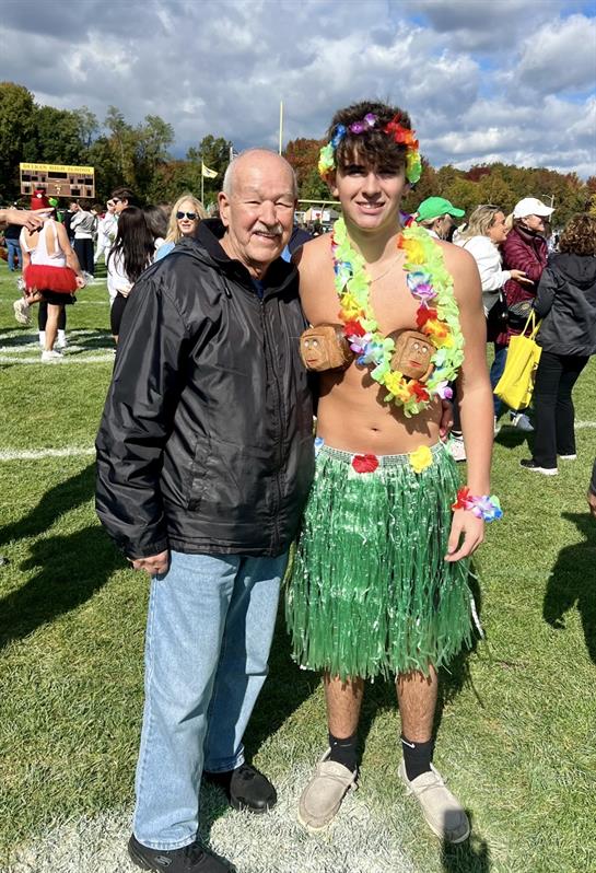 A man standing next to a man wearing a grass skirt and a flower garland