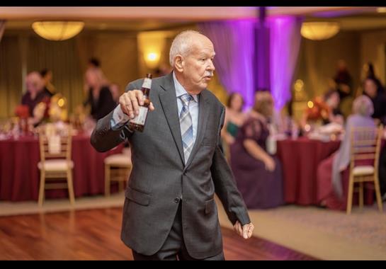 A man in a suit holding a bottle of beer