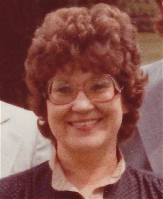 A cheerful woman with curly hair is enjoying an outdoor event surrounded by friends.