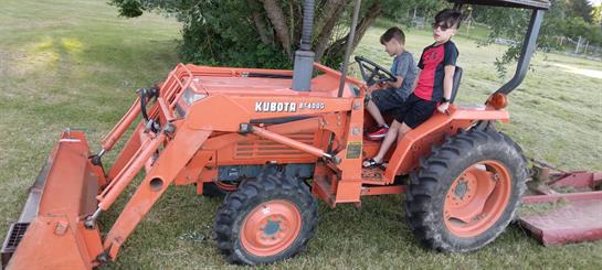 A couple of boys riding a tractor