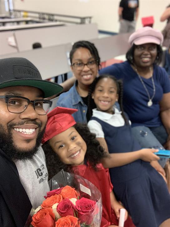 A joyful family gathers for a graduation ceremony, proudly celebrating the graduate in a red cap.