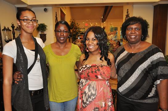 Four women share smiles and laughter in a warm restaurant, celebrating together in a joyful moment.