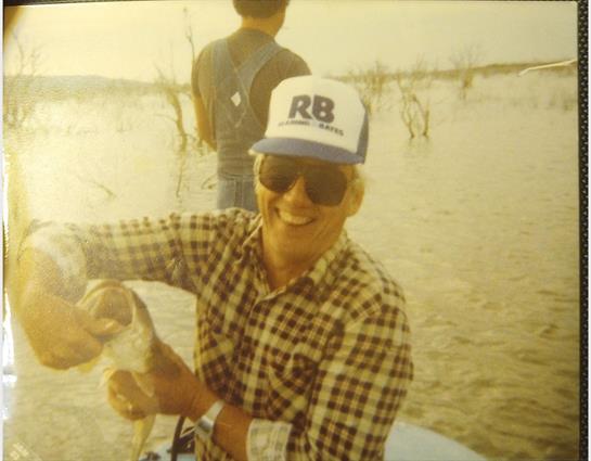 A fisherman proudly displays a large fish he just caught, enjoying his time at the lake.