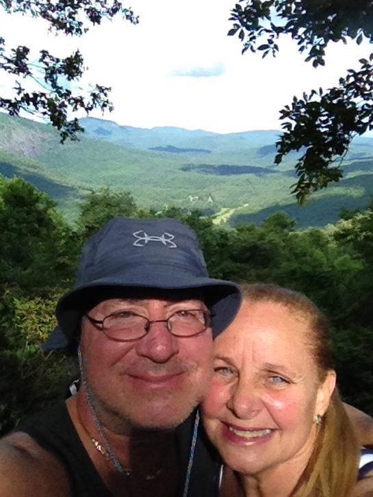 Happy couple takes a selfie while hiking in the mountains with a stunning background view.