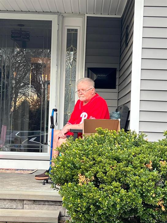 An old man sitting in a chair outside of a house