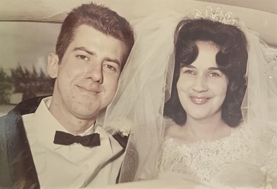 Newlyweds smile happily while posing together on their special day in a beautiful setting.