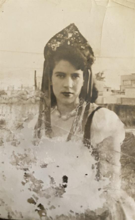 A young woman confidently wears intricate traditional attire in a dusty outdoor setting.