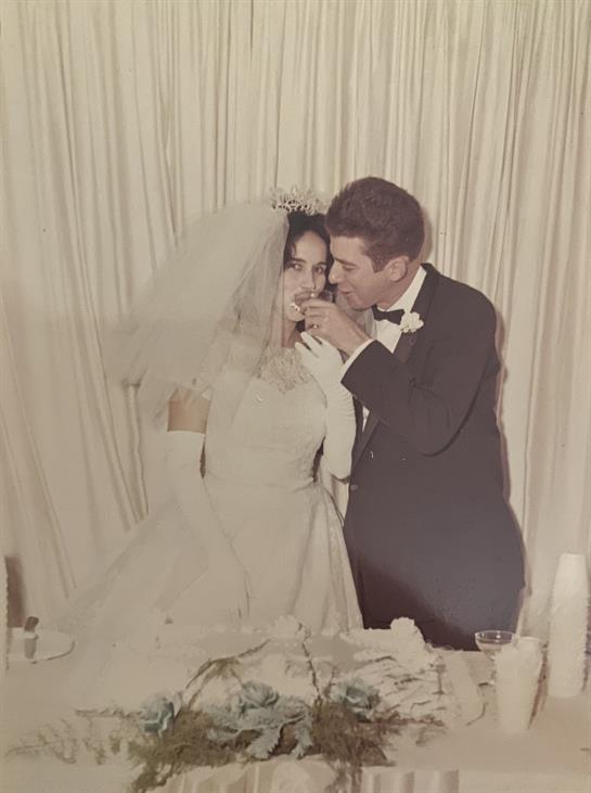 A newlywed couple shares cake during their wedding reception, surrounded by elegant decor.
