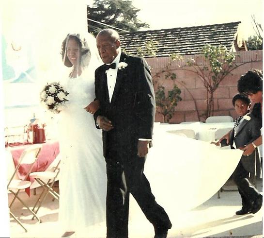 Couple walks hand in hand down the aisle at a joyful wedding ceremony on a bright day.
