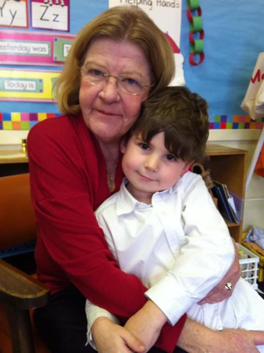 A teacher warmly embraces a young student in a cheerful classroom setting, fostering connection.
