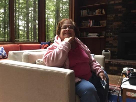 A woman sits comfortably in a well-lit living room, smiling and enjoying the tranquil atmosphere.