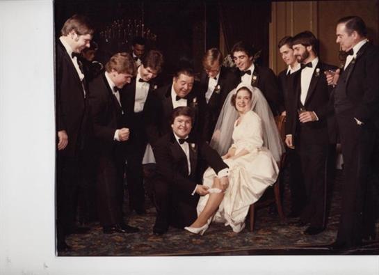 Groomsmen gather around bride, creating a lighthearted atmosphere during wedding festivities.