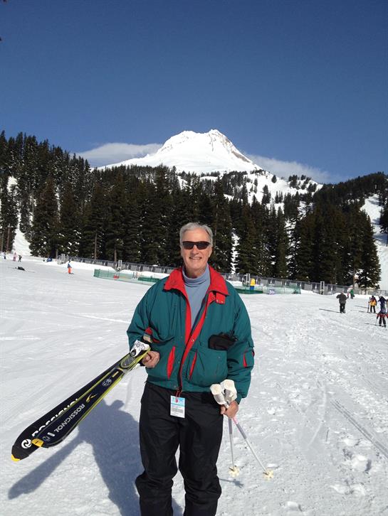 A man holding skis in front of a mountain
