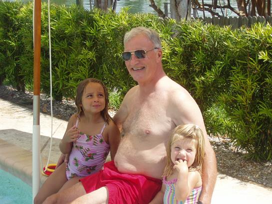 A man and two children sitting on a pool side