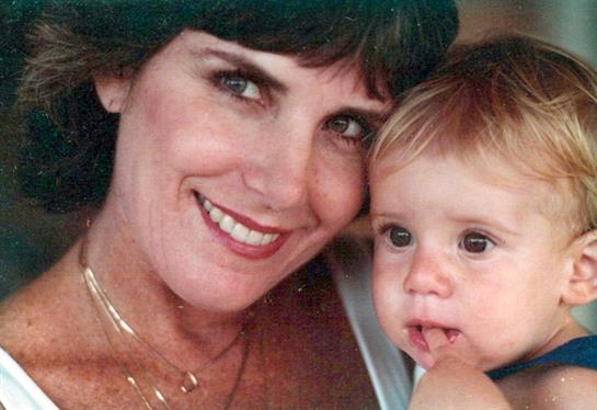 A joyful woman embraces a baby, both sharing a warm moment filled with laughter and love.
