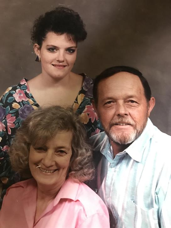 A family poses together with joyful expressions, showcasing their close bond and style.