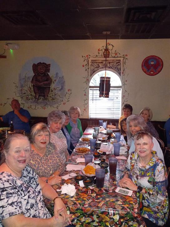 A lively gathering of friends sharing a meal in a charming, decorated restaurant.