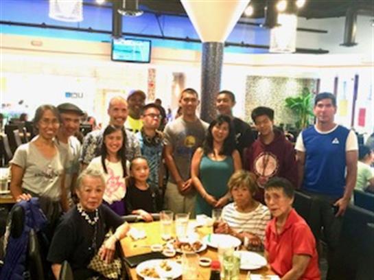 A diverse group of individuals poses happily at a dining table, celebrating and sharing food.