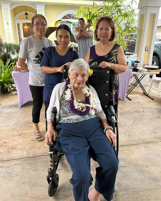 A vibrant family gathering featuring an elder in a wheelchair with loving relatives around her.