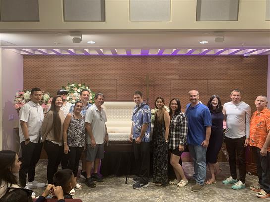A group of family members poses together in a hall during a celebration, smiling joyfully.