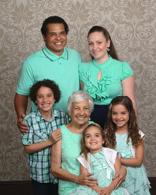 A joyful family poses in turquoise attire, showcasing love and connection against a floral backdrop.