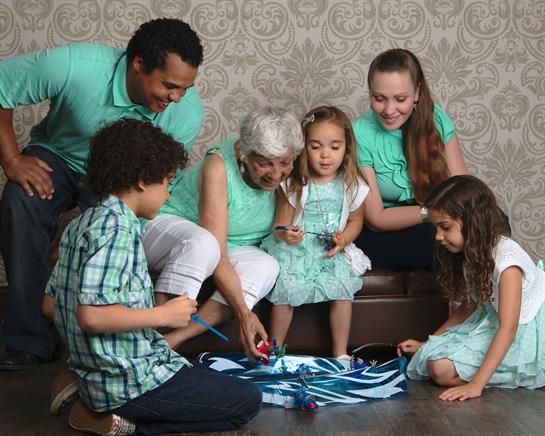 Children and adults engage in a fun art activity while wearing matching outfits, sharing laughter.