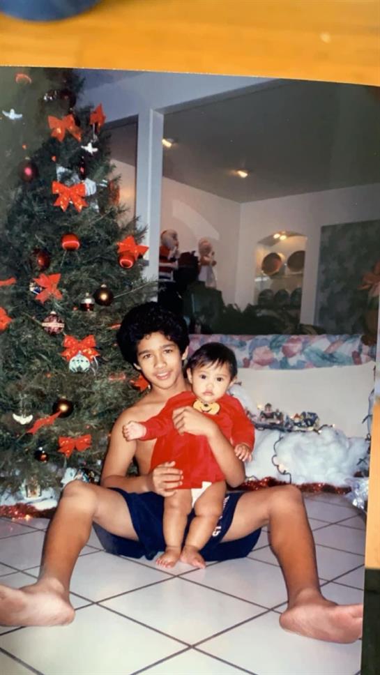 Two siblings enjoy Christmas time together in a warmly decorated living room.