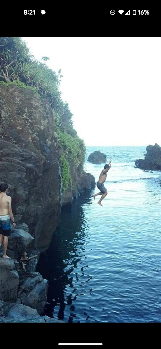 Two friends delight in cliff diving off rocky ledges into the tranquil blue waters below.