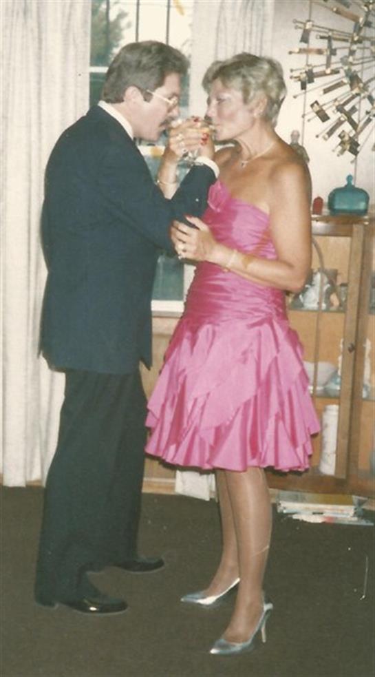 A couple enjoying a dance together in an elegantly decorated living room during a festive gathering.