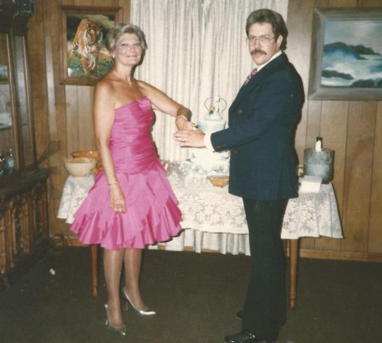 Couple dressed formally stands together, showcasing a celebratory atmosphere with decor.