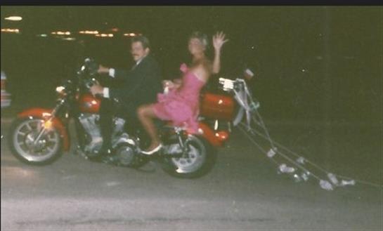A couple rides a decorated motorcycle at night, celebrating joyfully together.