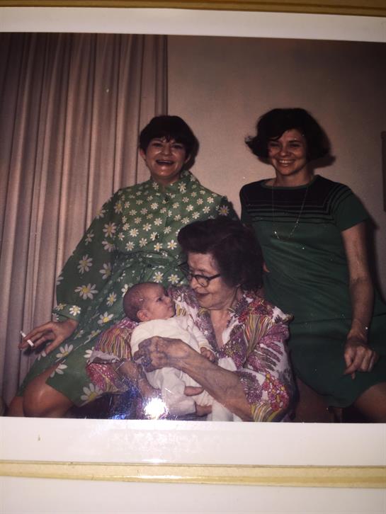 Four women enjoy a moment together with a baby in a warm, inviting environment.