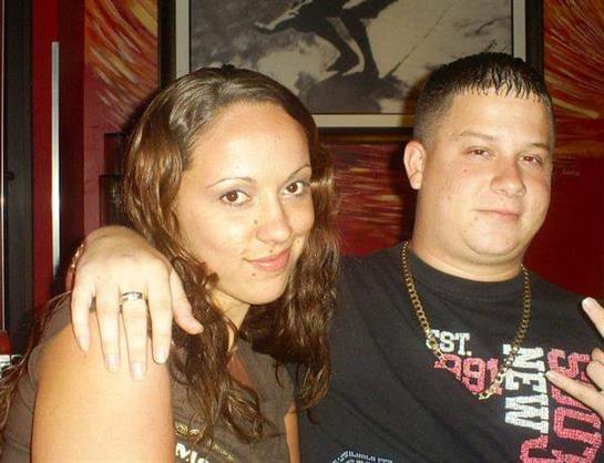 Two individuals are sharing a joyful moment at a lively bar, surrounded by colorful decor.