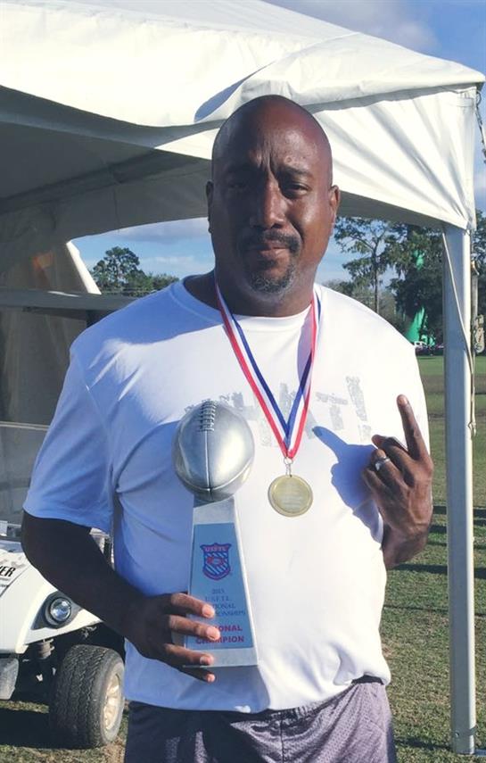 A proud athlete poses with a trophy and medal after winning a sports competition outdoors.