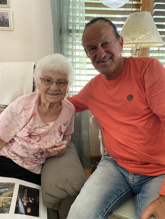 Warm interaction between an elderly woman and a man in casual attire while sharing memories.