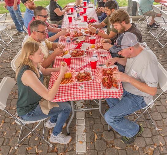 Friends gather around a picnic table sharing food and drinks while enjoying each other's company.